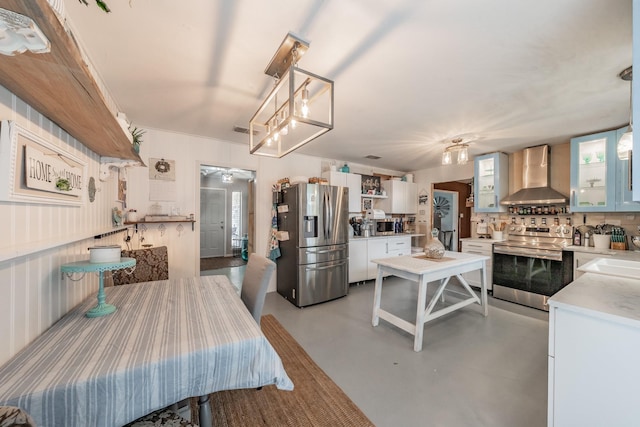 kitchen with white cabinetry, wall chimney exhaust hood, tasteful backsplash, decorative light fixtures, and appliances with stainless steel finishes