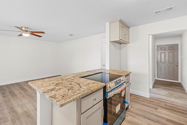 kitchen featuring stainless steel range with electric stovetop, light stone countertops, ceiling fan, and light hardwood / wood-style flooring