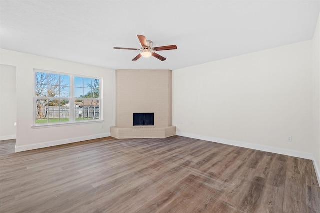 unfurnished living room featuring a brick fireplace, hardwood / wood-style floors, and ceiling fan