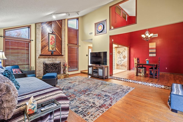 living room featuring track lighting, a fireplace, a textured ceiling, hardwood / wood-style flooring, and a chandelier