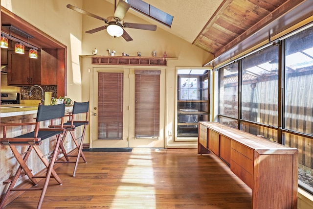 sunroom with lofted ceiling with skylight, sink, ceiling fan, and wood ceiling