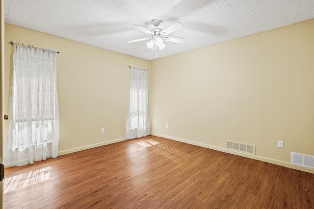 spare room with ceiling fan, hardwood / wood-style floors, a healthy amount of sunlight, and a textured ceiling