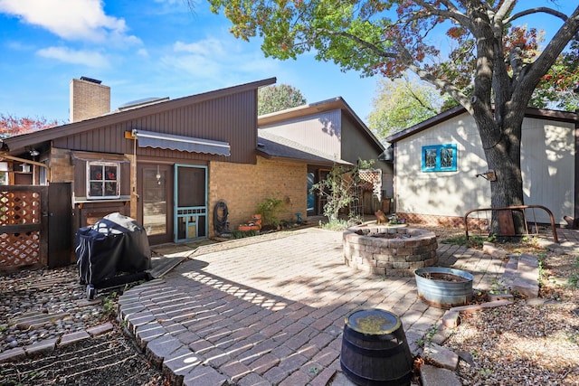 rear view of property featuring a patio and an outdoor fire pit