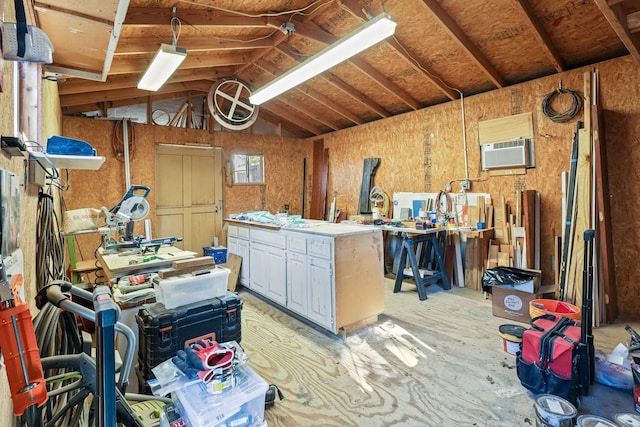 miscellaneous room featuring a workshop area, a wall unit AC, and vaulted ceiling