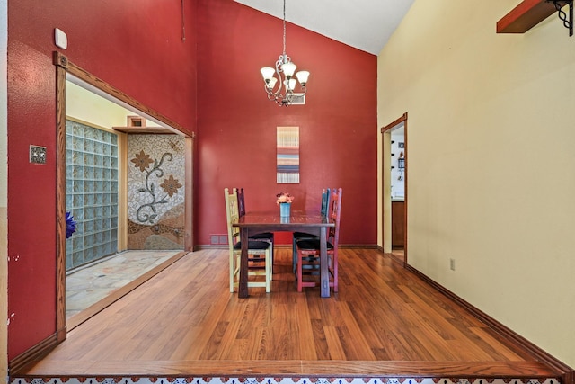 dining area with hardwood / wood-style floors, high vaulted ceiling, and a notable chandelier