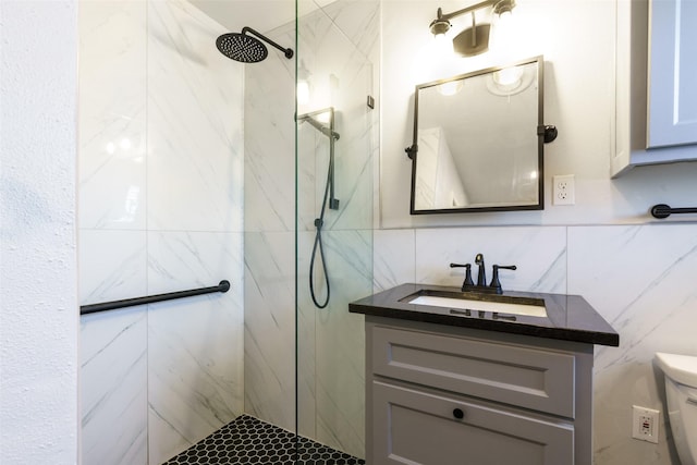 bathroom with vanity, toilet, tiled shower, and tile walls