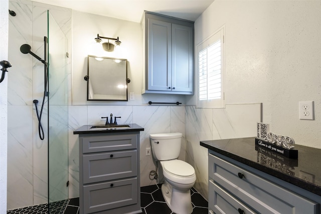 bathroom with a tile shower, toilet, tile walls, and vanity