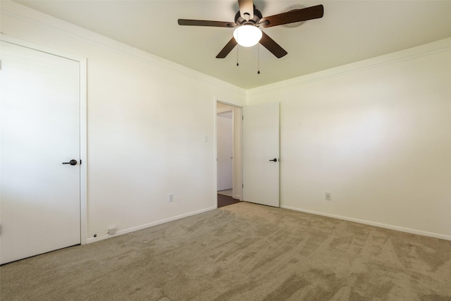 carpeted empty room featuring ceiling fan and ornamental molding