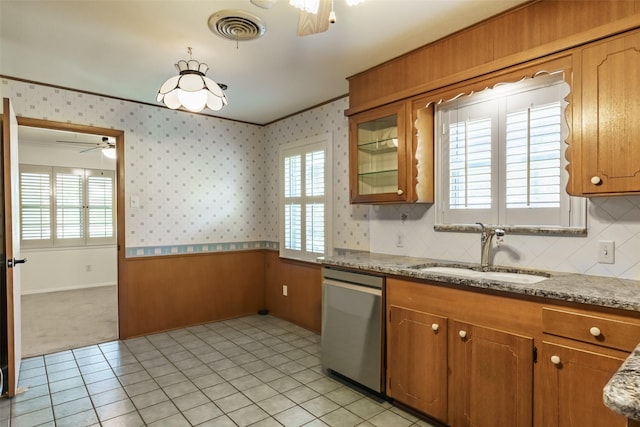 kitchen featuring light stone countertops, light tile patterned floors, stainless steel dishwasher, sink, and ceiling fan