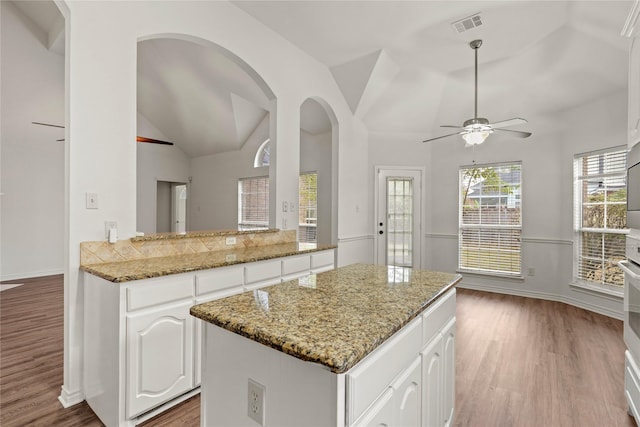 kitchen featuring hardwood / wood-style floors, white cabinetry, vaulted ceiling, and ceiling fan