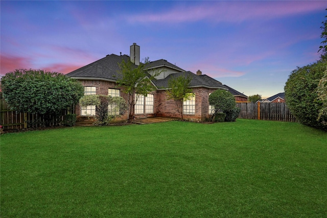 back house at dusk featuring a yard