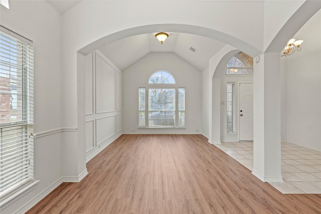 foyer featuring light hardwood / wood-style floors, lofted ceiling, and a notable chandelier