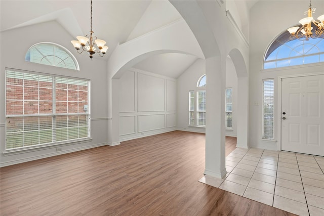 foyer entrance featuring a healthy amount of sunlight, high vaulted ceiling, and a chandelier