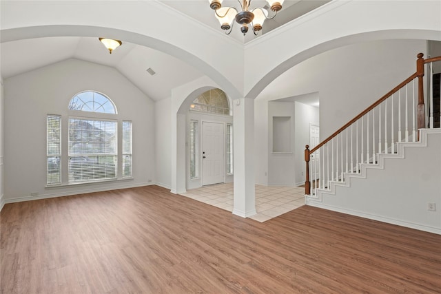 foyer with vaulted ceiling, an inviting chandelier, light hardwood / wood-style flooring, and crown molding