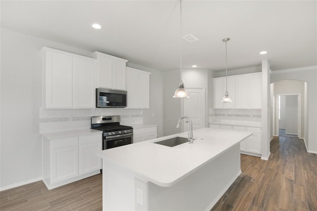 kitchen with stainless steel appliances, sink, wood-type flooring, a center island with sink, and white cabinets