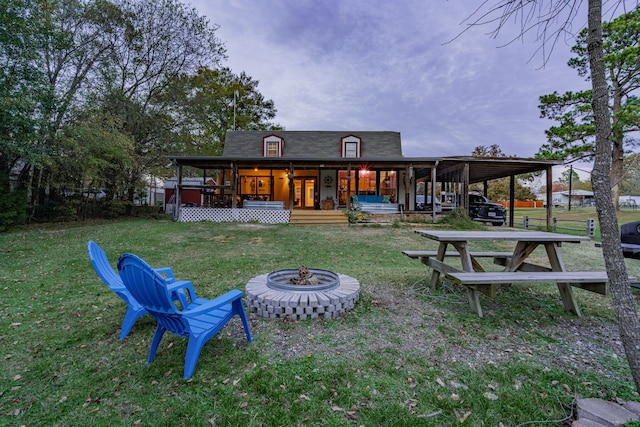 rear view of house featuring a yard, covered porch, a fire pit, and a carport