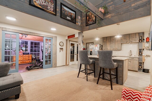 kitchen featuring a breakfast bar, appliances with stainless steel finishes, kitchen peninsula, a towering ceiling, and decorative backsplash