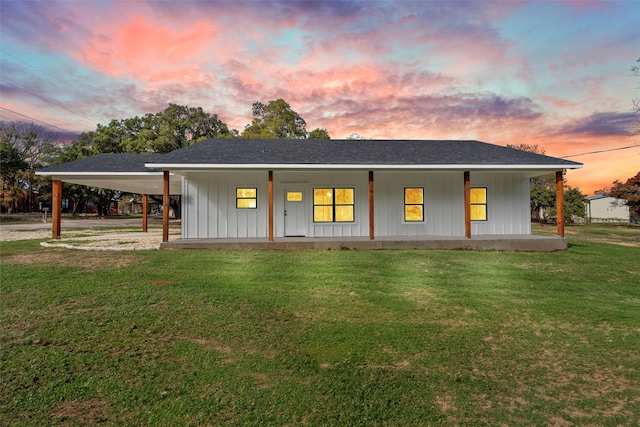 back house at dusk featuring a lawn