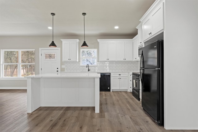 kitchen with tasteful backsplash, decorative light fixtures, a center island, black appliances, and white cabinets