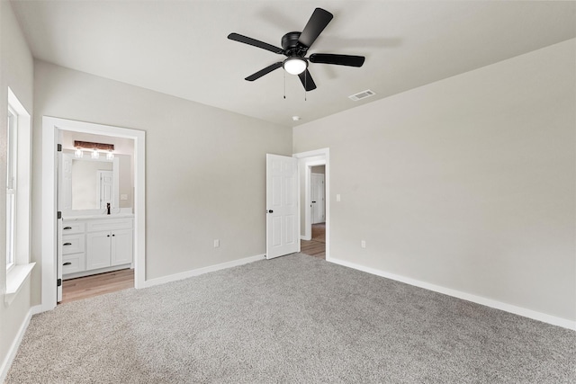 unfurnished bedroom featuring light carpet, connected bathroom, and ceiling fan