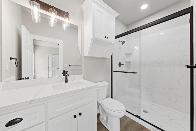 bathroom with wood-type flooring, toilet, vanity, and walk in shower