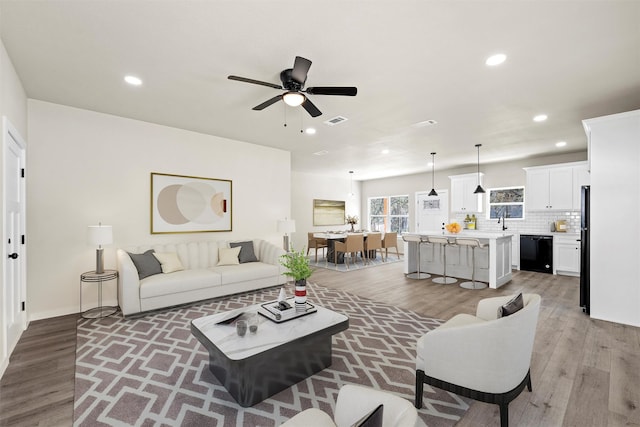 living room featuring sink, light hardwood / wood-style floors, and ceiling fan