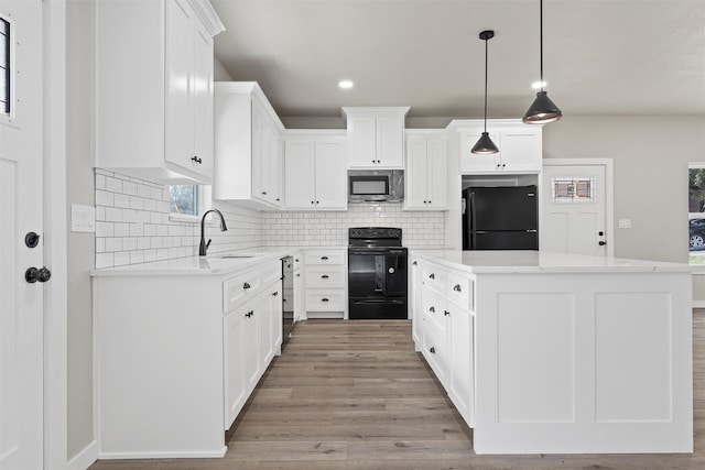 kitchen featuring white cabinetry, a kitchen island, sink, and black appliances