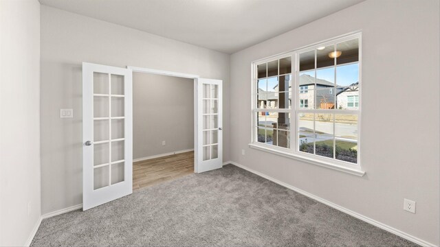 carpeted spare room featuring french doors