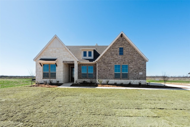 view of front of property featuring stone siding, brick siding, and a front yard