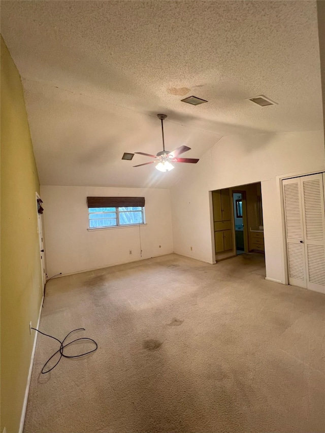 carpeted spare room with a textured ceiling, ceiling fan, and lofted ceiling