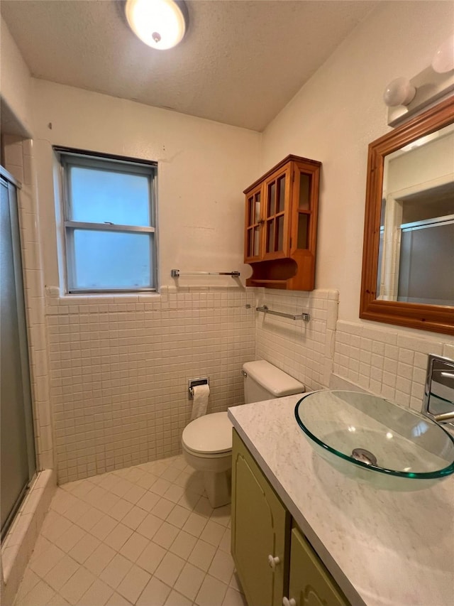 bathroom with tile patterned flooring, vanity, a shower with door, and tile walls