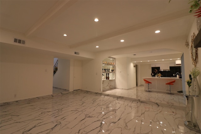 empty room with beam ceiling and wet bar