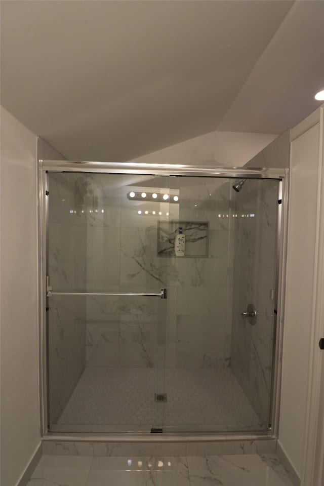 bathroom featuring a shower with shower door and lofted ceiling