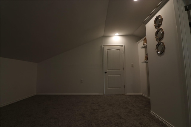 bonus room with dark colored carpet and lofted ceiling