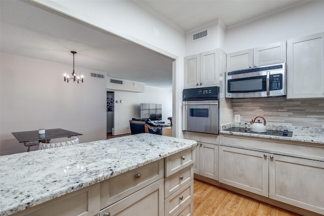 kitchen featuring appliances with stainless steel finishes, backsplash, crown molding, light hardwood / wood-style flooring, and a chandelier