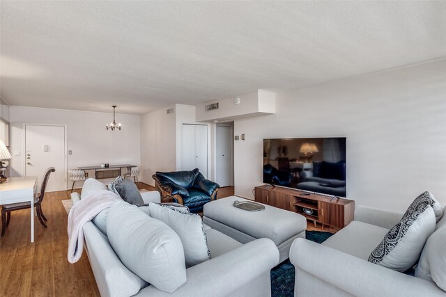 living room with hardwood / wood-style floors, a textured ceiling, and a notable chandelier