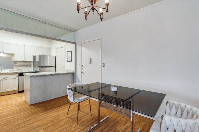 dining area with a chandelier, sink, crown molding, and light hardwood / wood-style flooring