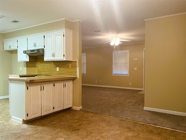 kitchen with white cabinetry, light colored carpet, ornamental molding, ceiling fan, and backsplash