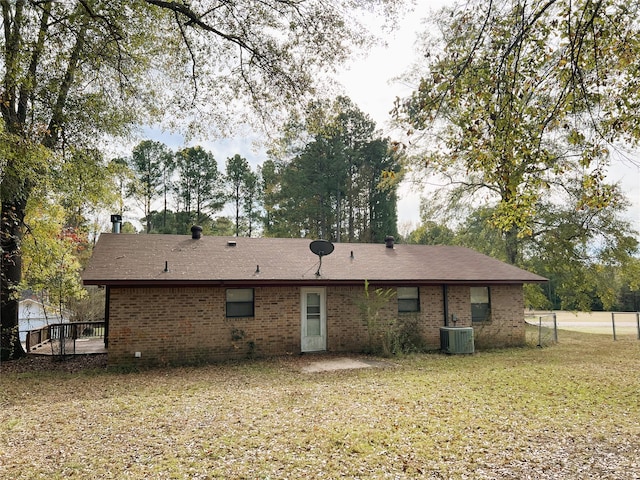 back of house with central AC unit and a lawn