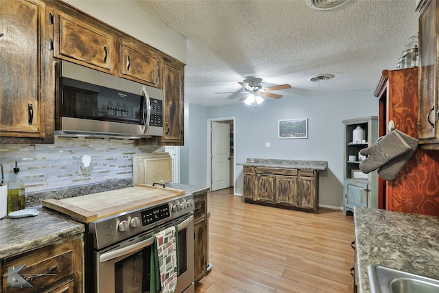 kitchen featuring decorative backsplash, a textured ceiling, appliances with stainless steel finishes, and light hardwood / wood-style flooring