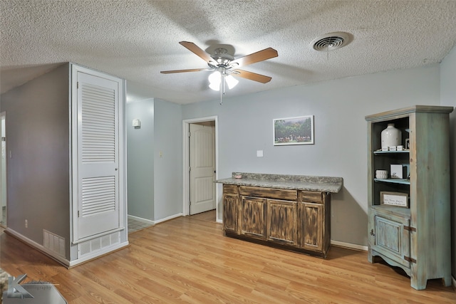 interior space featuring a textured ceiling, light hardwood / wood-style floors, and ceiling fan