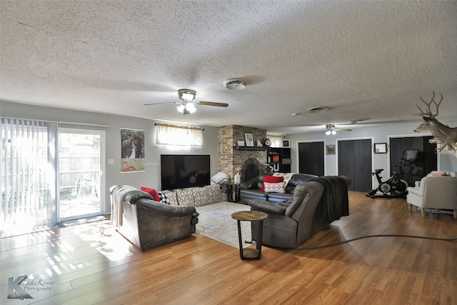 living room with a textured ceiling, light wood-type flooring, and ceiling fan