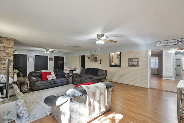 living room featuring a textured ceiling, hardwood / wood-style flooring, and brick wall