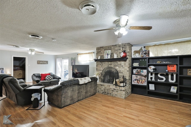 living room featuring hardwood / wood-style flooring, a fireplace, ceiling fan, and a textured ceiling