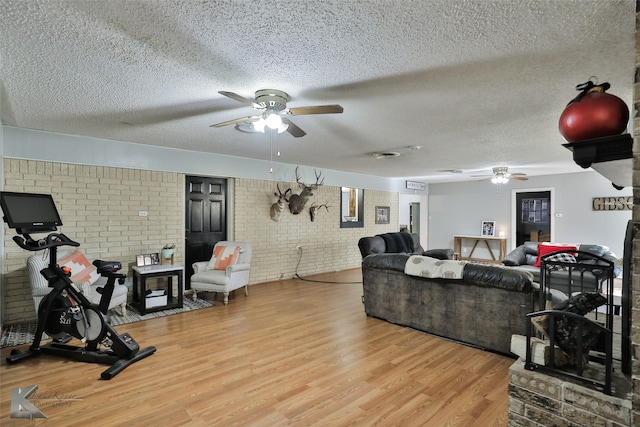 living room featuring a textured ceiling, light hardwood / wood-style floors, and brick wall