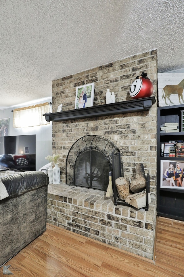 details featuring a textured ceiling, hardwood / wood-style flooring, and a brick fireplace