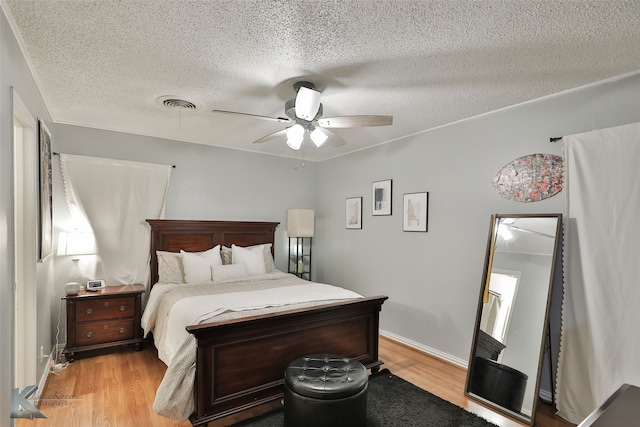 bedroom featuring ceiling fan, light wood-type flooring, and a textured ceiling