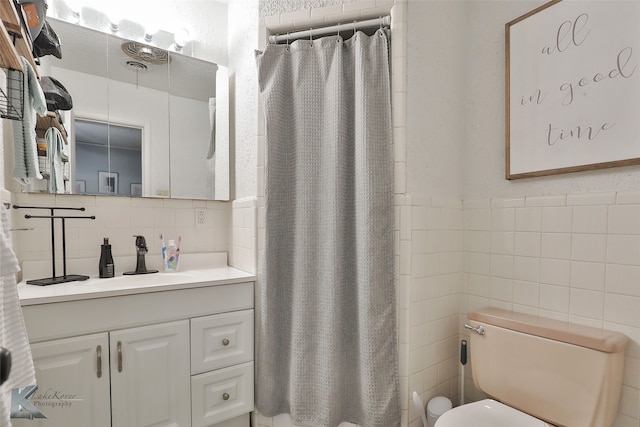 bathroom featuring curtained shower, vanity, tile walls, and toilet