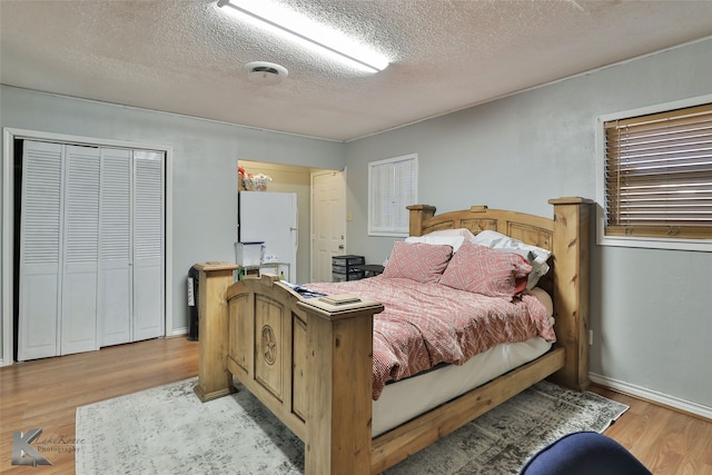 bedroom featuring a closet, a textured ceiling, and light hardwood / wood-style flooring