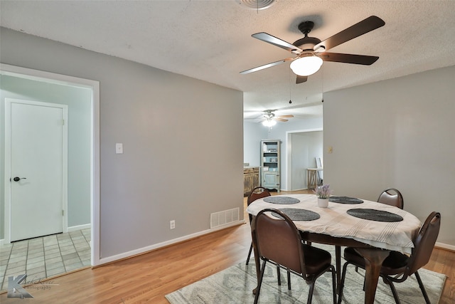 dining room with ceiling fan, a textured ceiling, and light hardwood / wood-style flooring